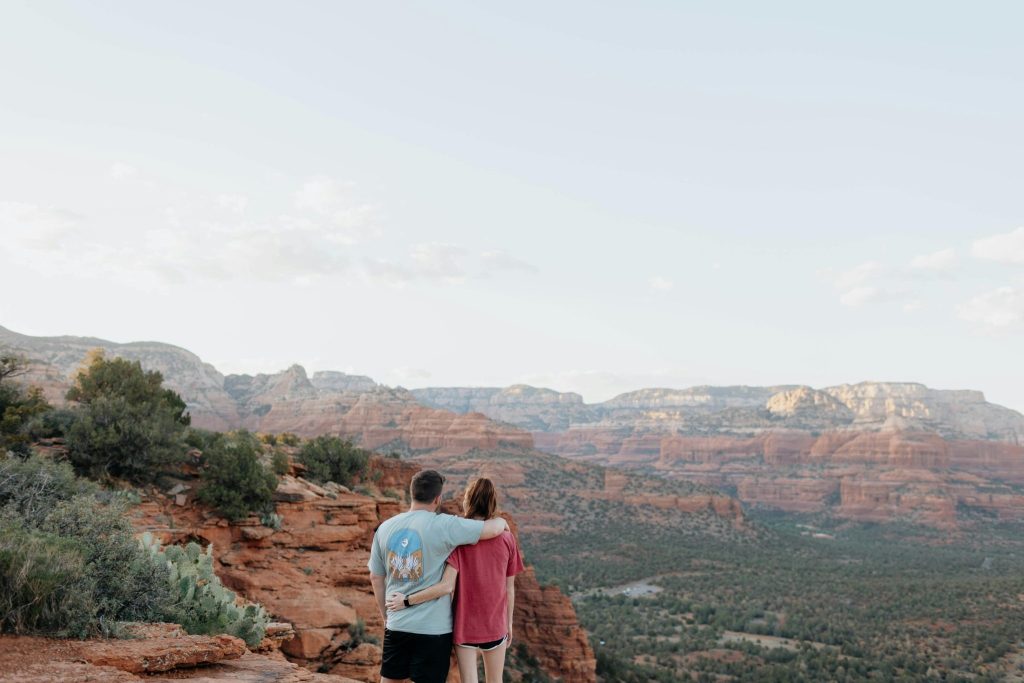 Couple embracing while overlooking red rock canyon landscape at sunset